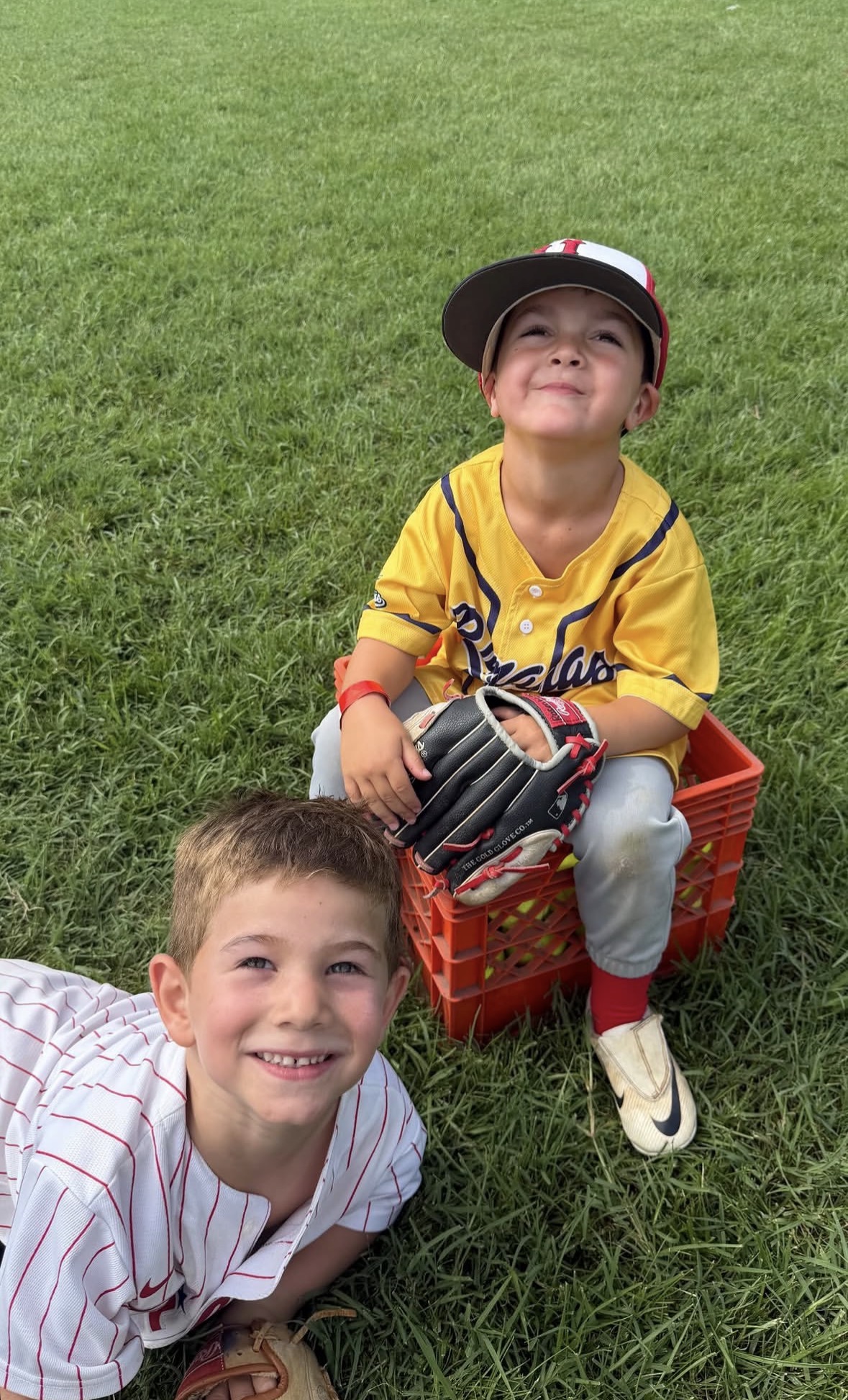 Two young WIN campers smiling together on the outfield grass