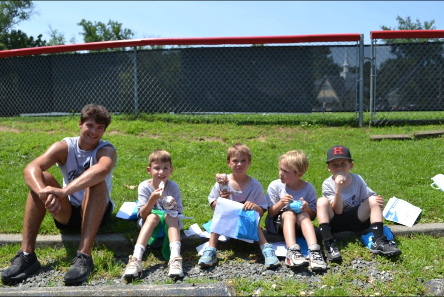 A coach and campers taking an ice cream break beside the field