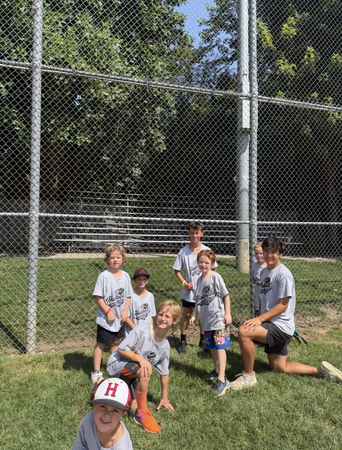 Campers and their coach kneeling in the grass beside the field